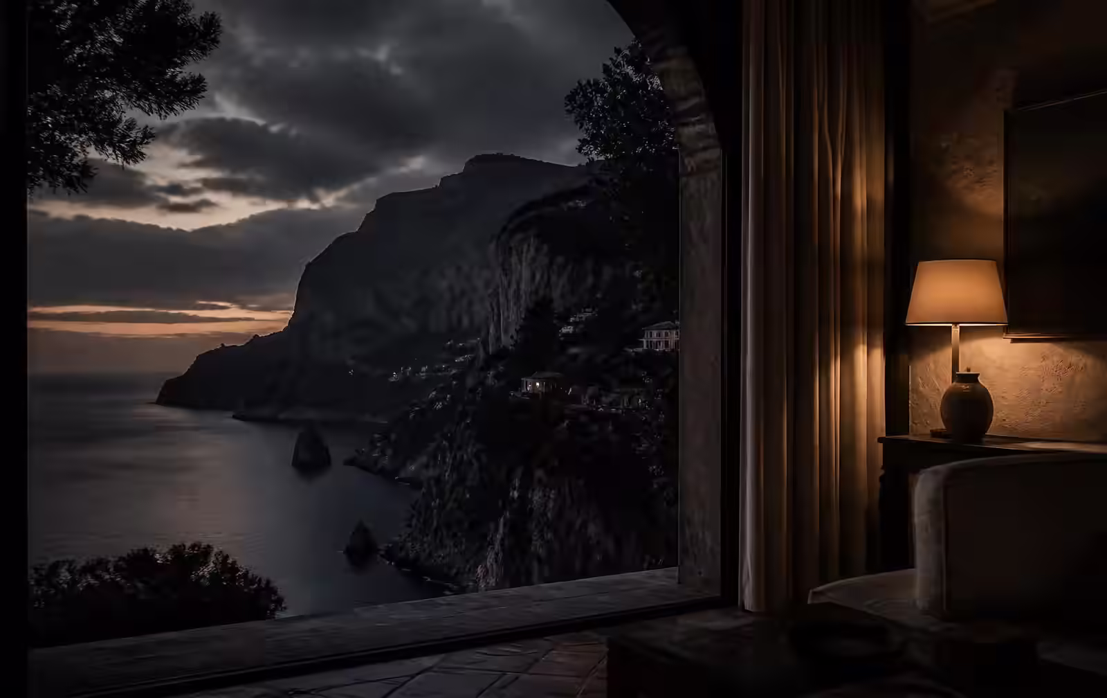 A Mediterranean cliff coastline at deep dusk seen from a warmly lit stone interior