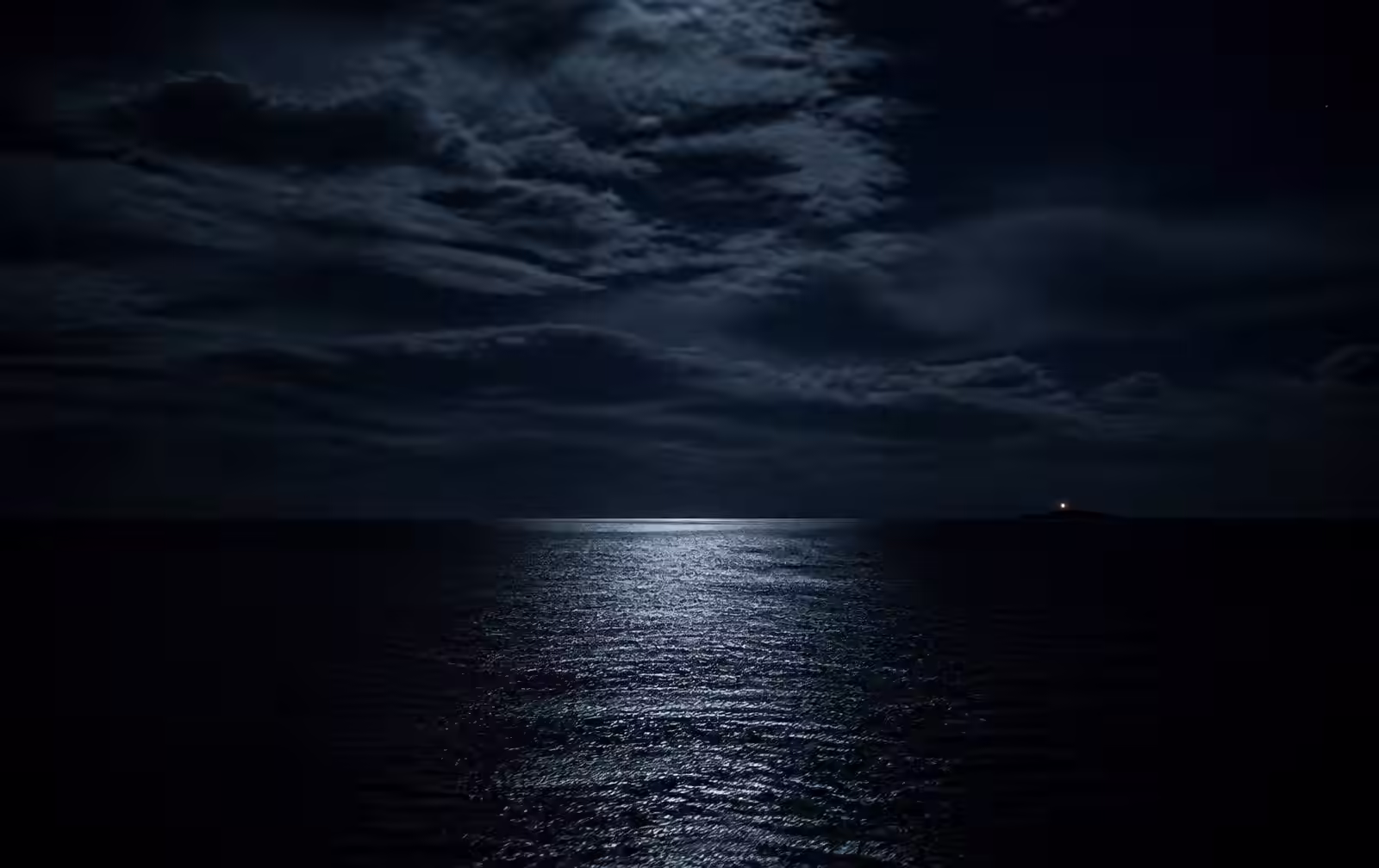 A vast dark ocean at night with a narrow band of moonlight and one distant island light