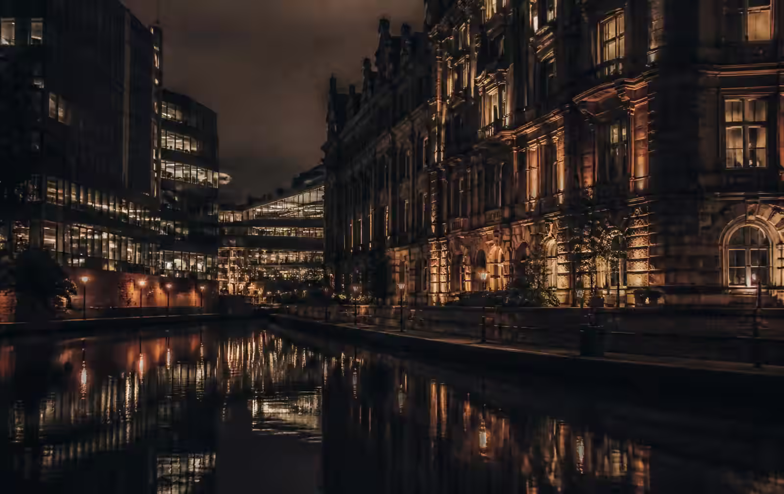 Birmingham canal at night with Victorian stone facade and modern glass reflected in dark water