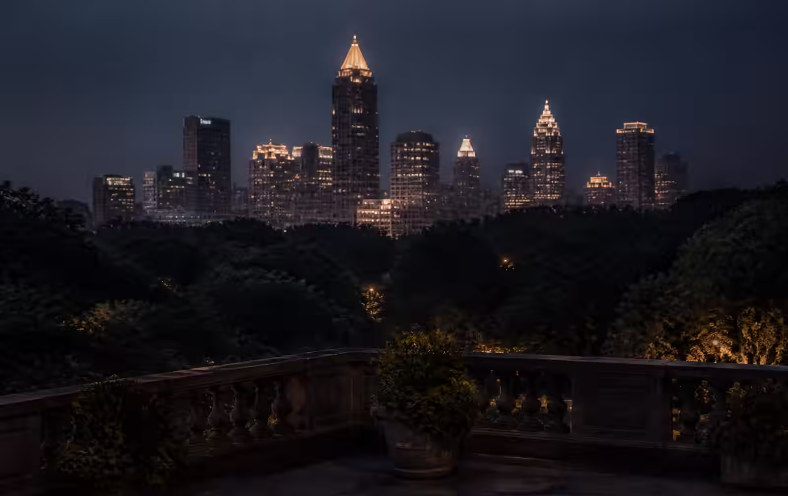 Dim high-rise hotel room in Atlanta with city lights spread out beyond floor-to-ceiling glass