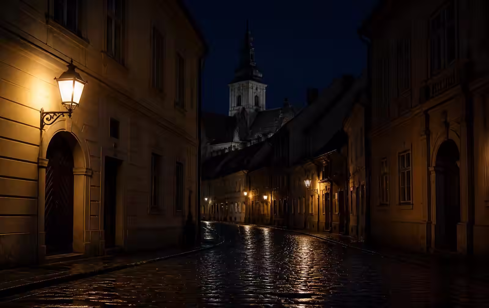 Zagreb's Upper Town at night — a gas-lit cobbled lane glistening after rain beneath a church spire