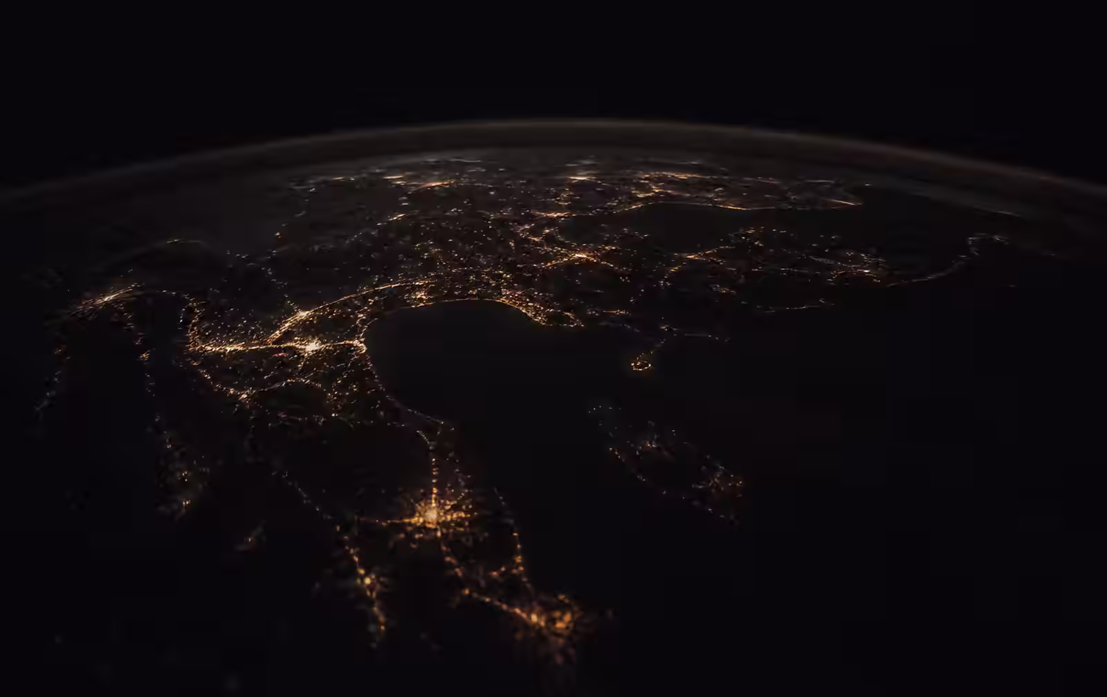 The curve of the earth at night, scattered with distant golden city lights