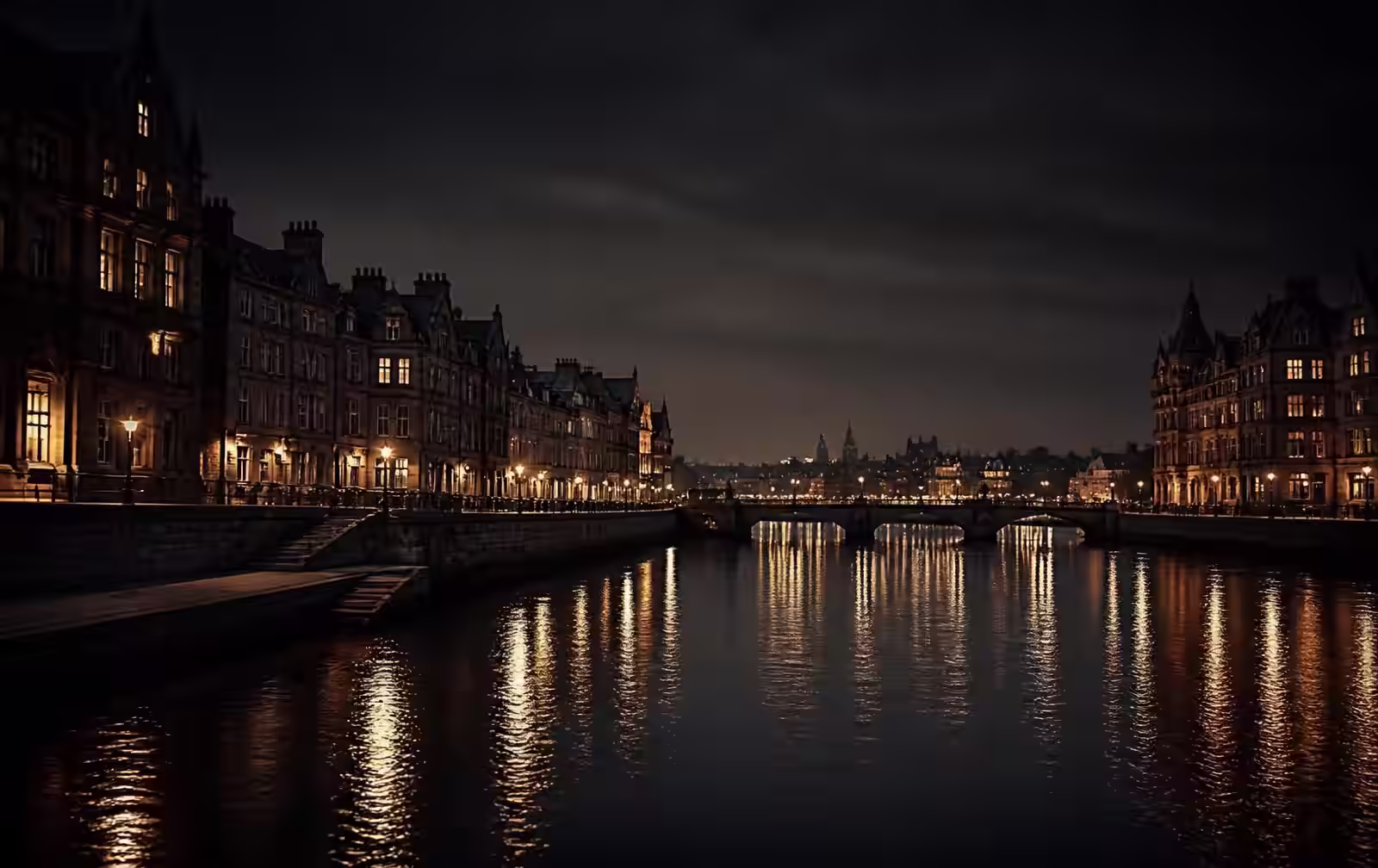 A dark granite river city at night with warm window light reflected on still water