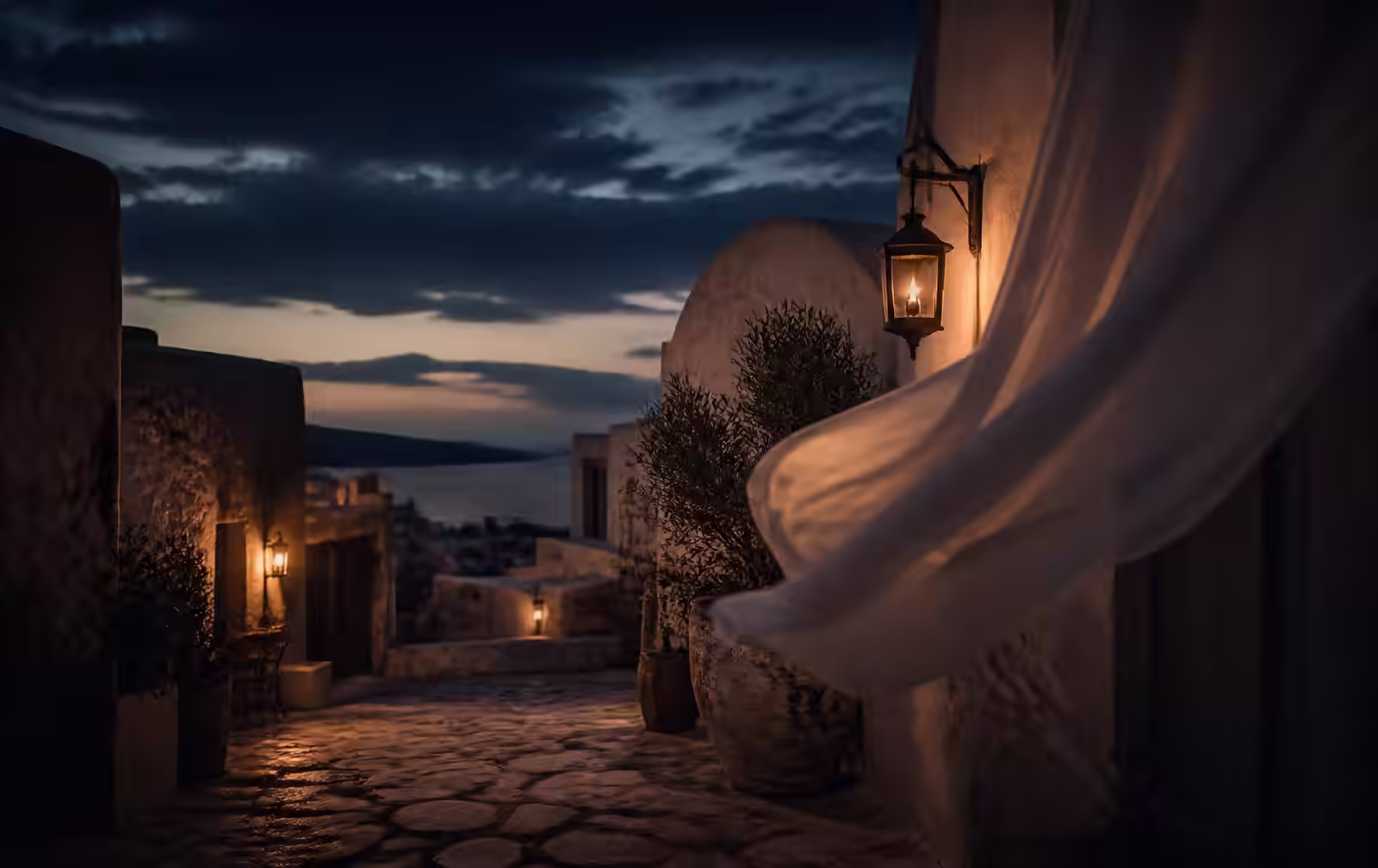 A pale stone lane at summer dusk with a lantern and linen moving in the wind, sea visible beyond