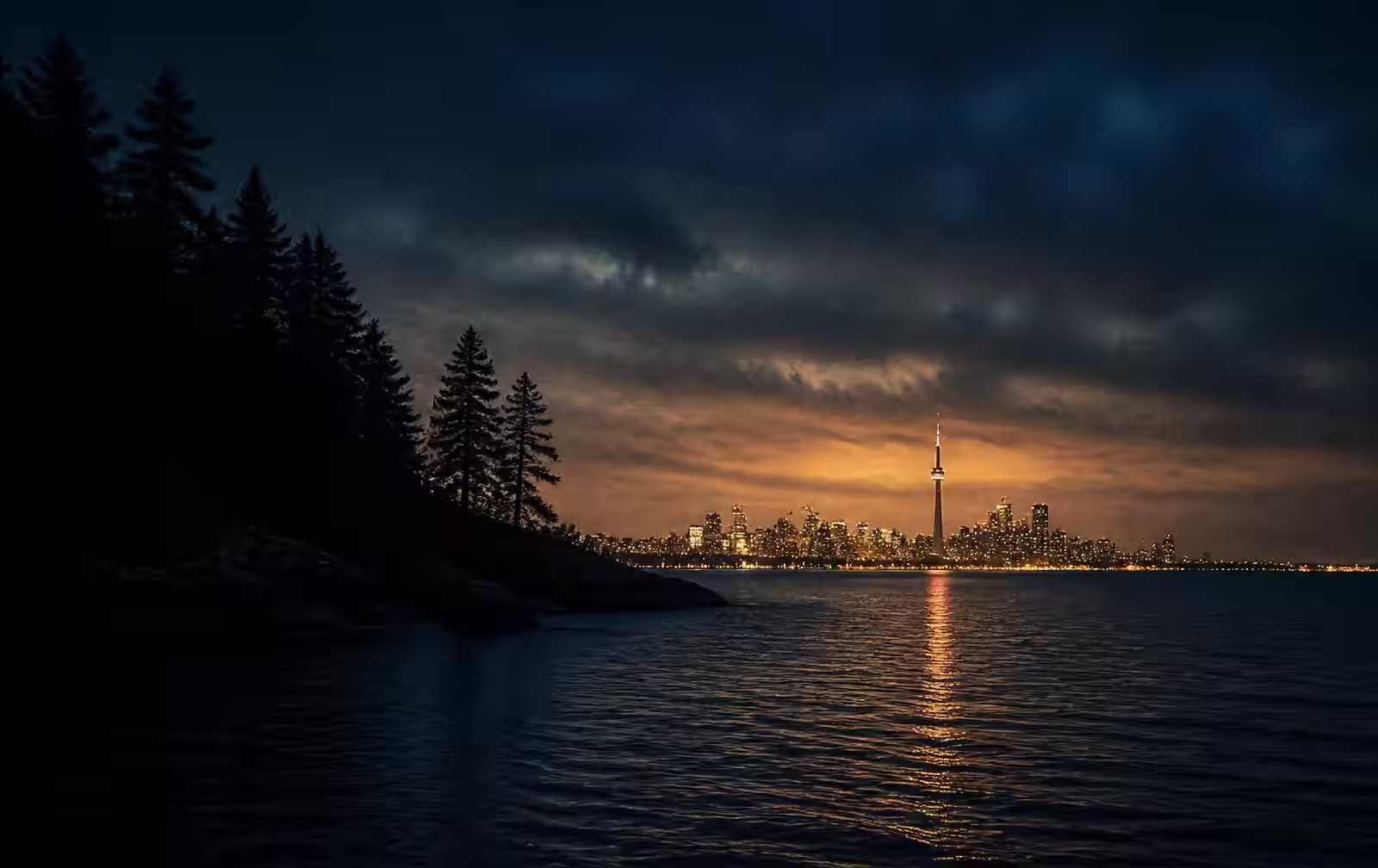 Dark Ontario lake at dusk with pine shoreline and a single warm cottage light across the water