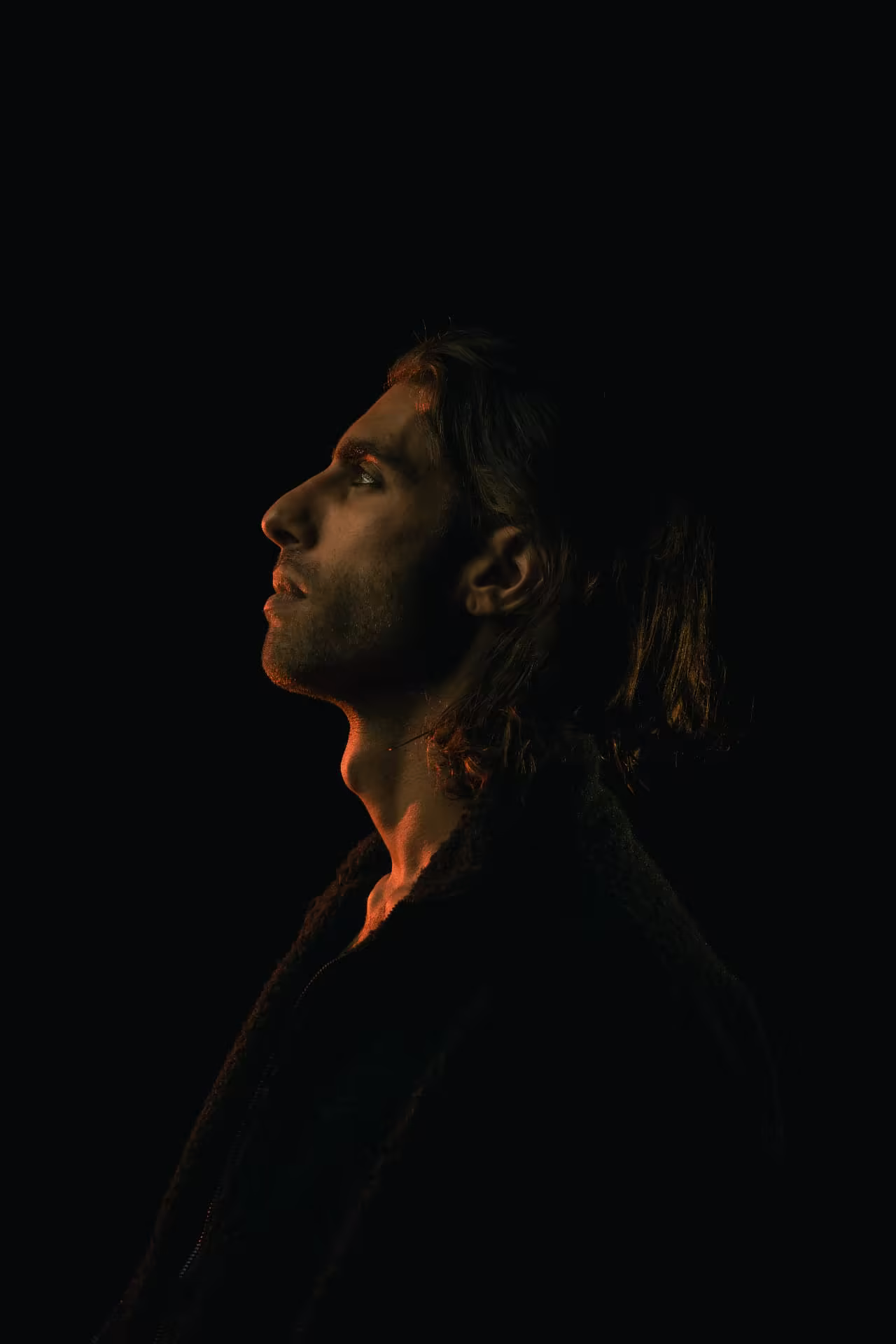 Lucianno Vargas in profile, almost lost in darkness, traced by warm light