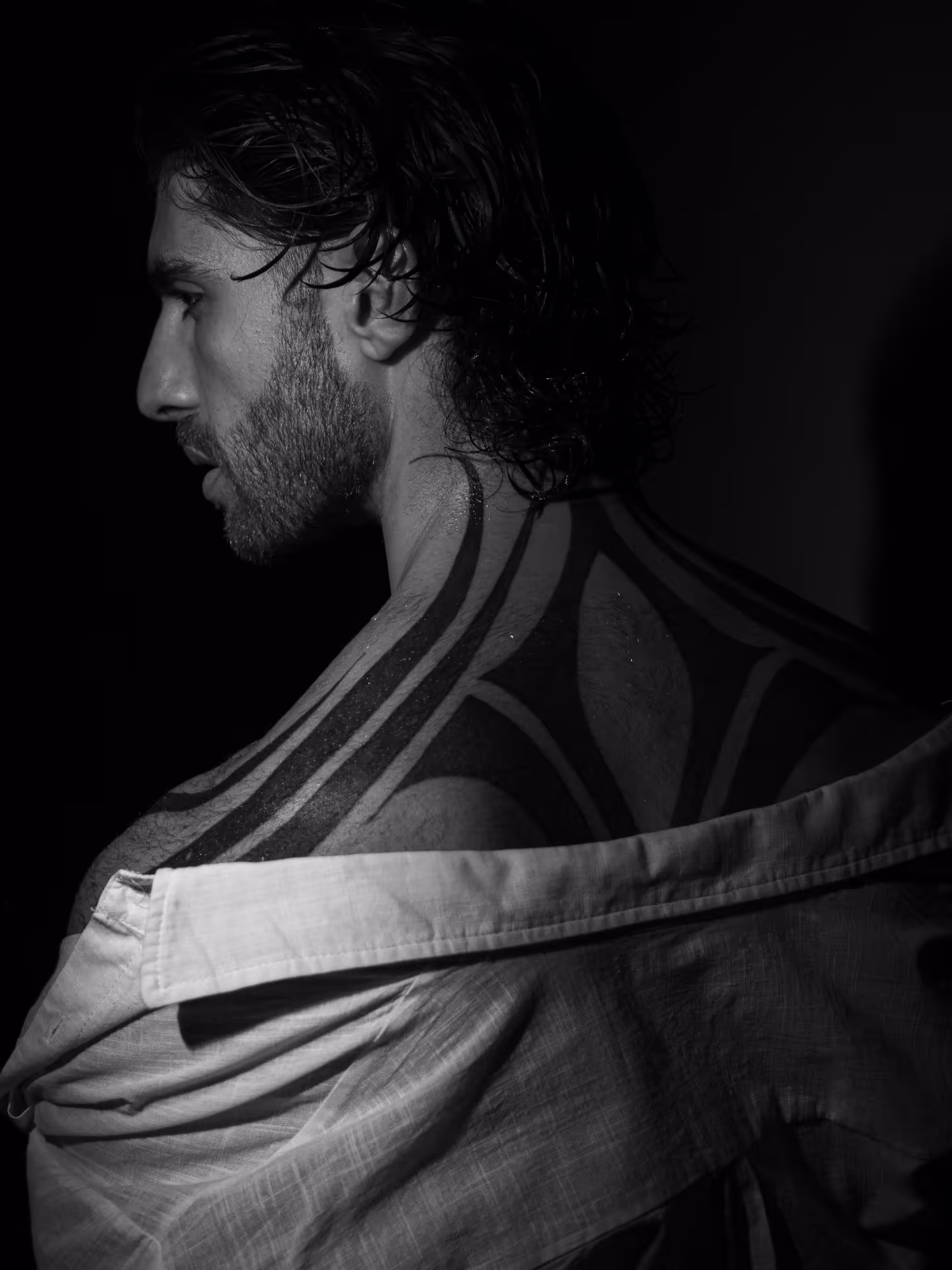Black-and-white portrait of Lucianno Vargas, shirt slipped from a tattooed shoulder