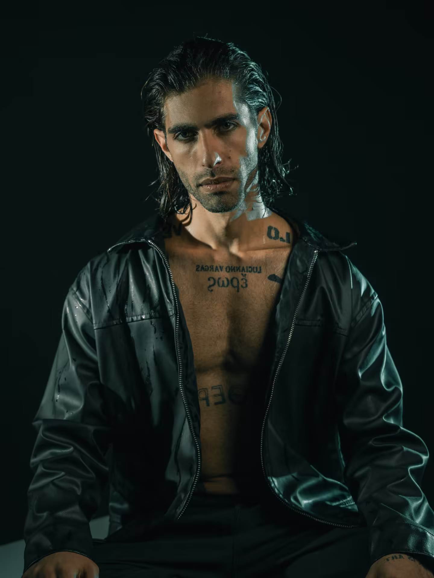 Lucianno Vargas in a wet-look leather jacket, meeting the camera's gaze