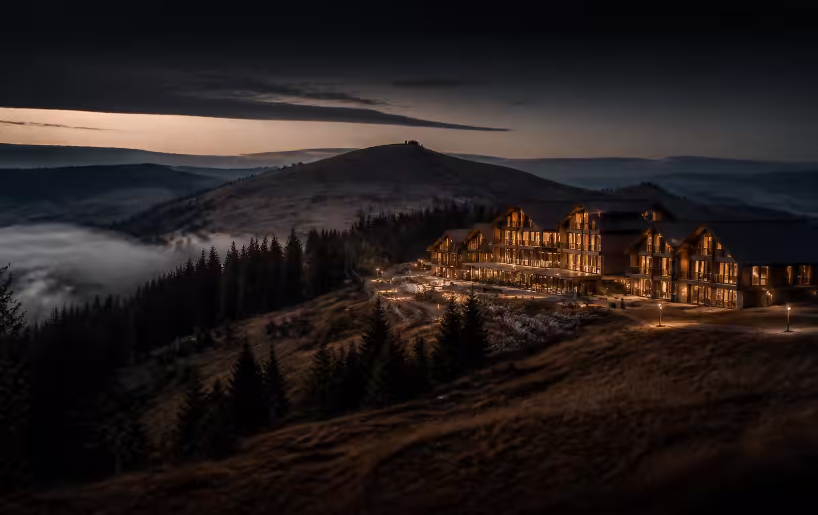 A rolling Serbian mountain plateau at dusk with a contemporary timber resort lit warm gold above misty valleys
