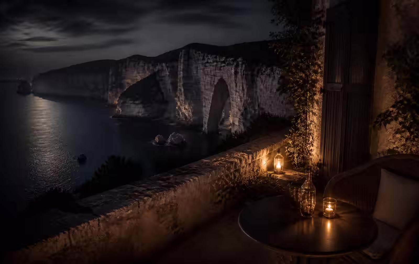 Pale limestone cliffs above dark Atlantic water at dusk with a single lit terrace