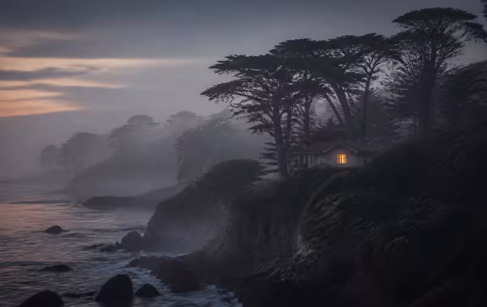 Misty Carmel coastline at dawn with cypress trees and a private cottage glowing softly through the fog