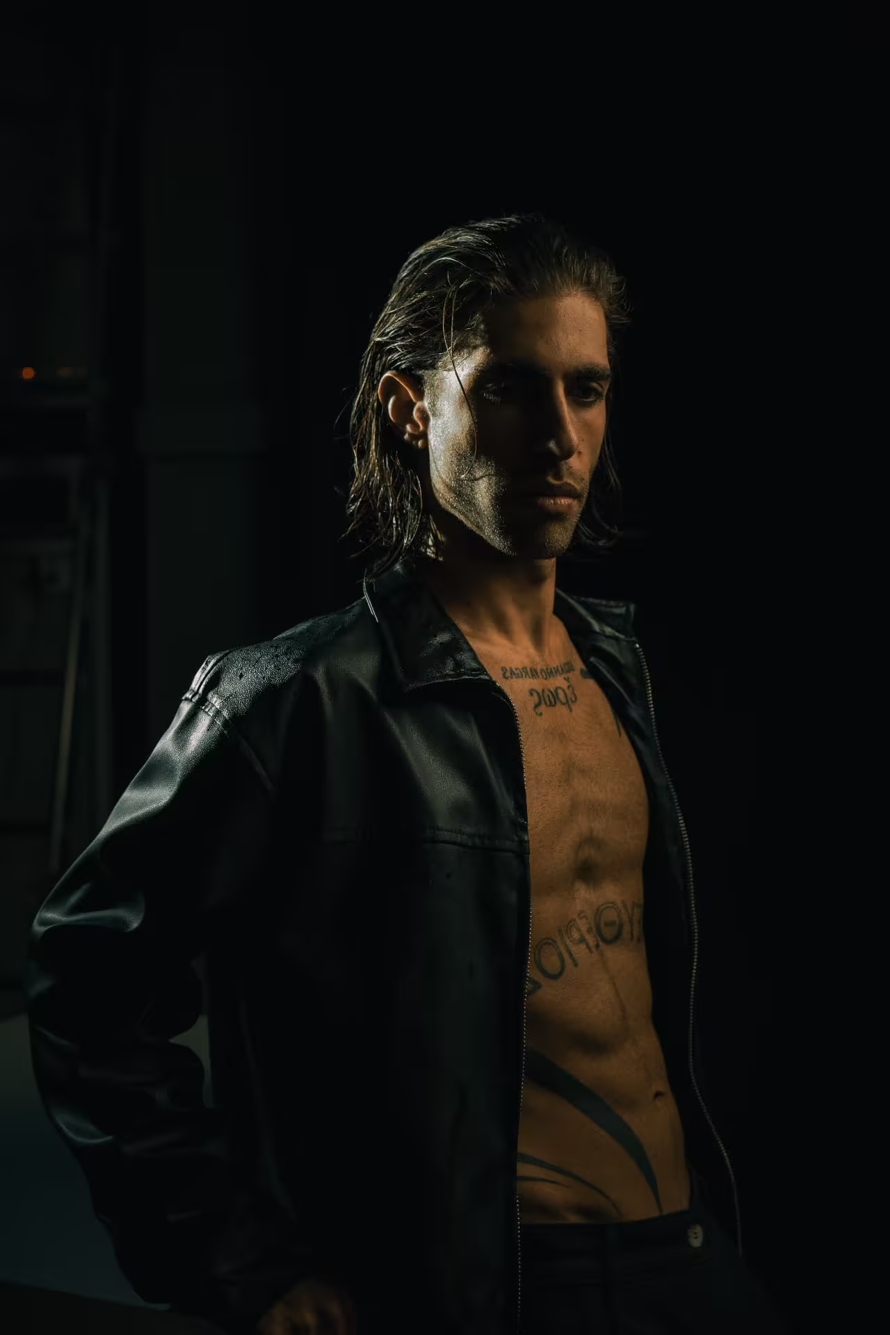 Lucianno Vargas in a dark leather shirt, half in shadow