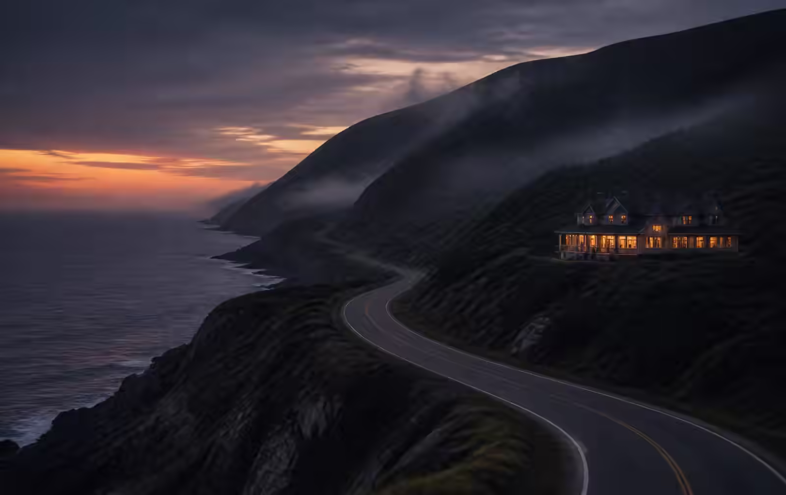 Empty coastal road curving along dark Cape Breton cliffs at dusk with an isolated lit lodge above the sea
