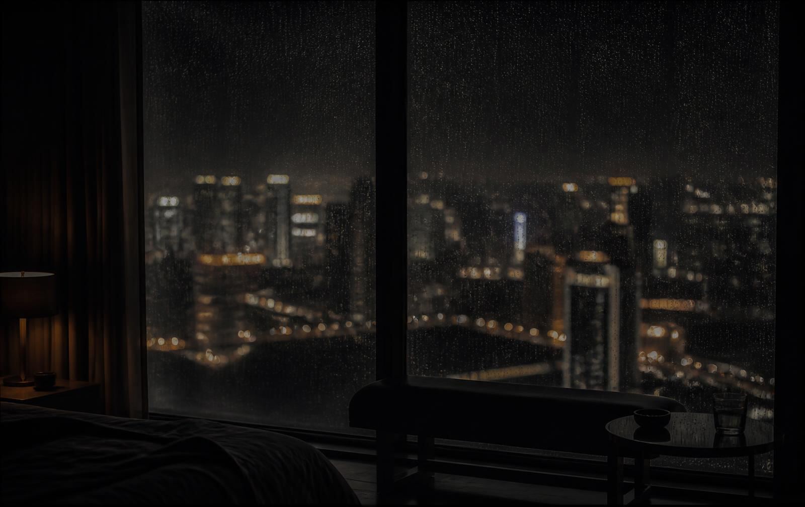 A rain-streaked window of a dark hotel suite overlooking distant city lights at night