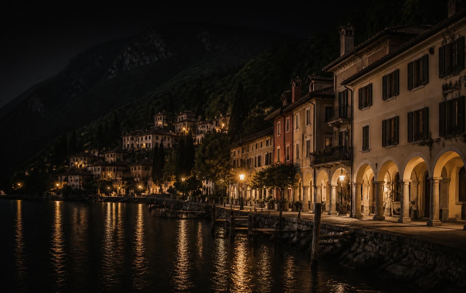 A quiet Italianate lakeside village at night with arcaded facades, gold lamplight and dark water