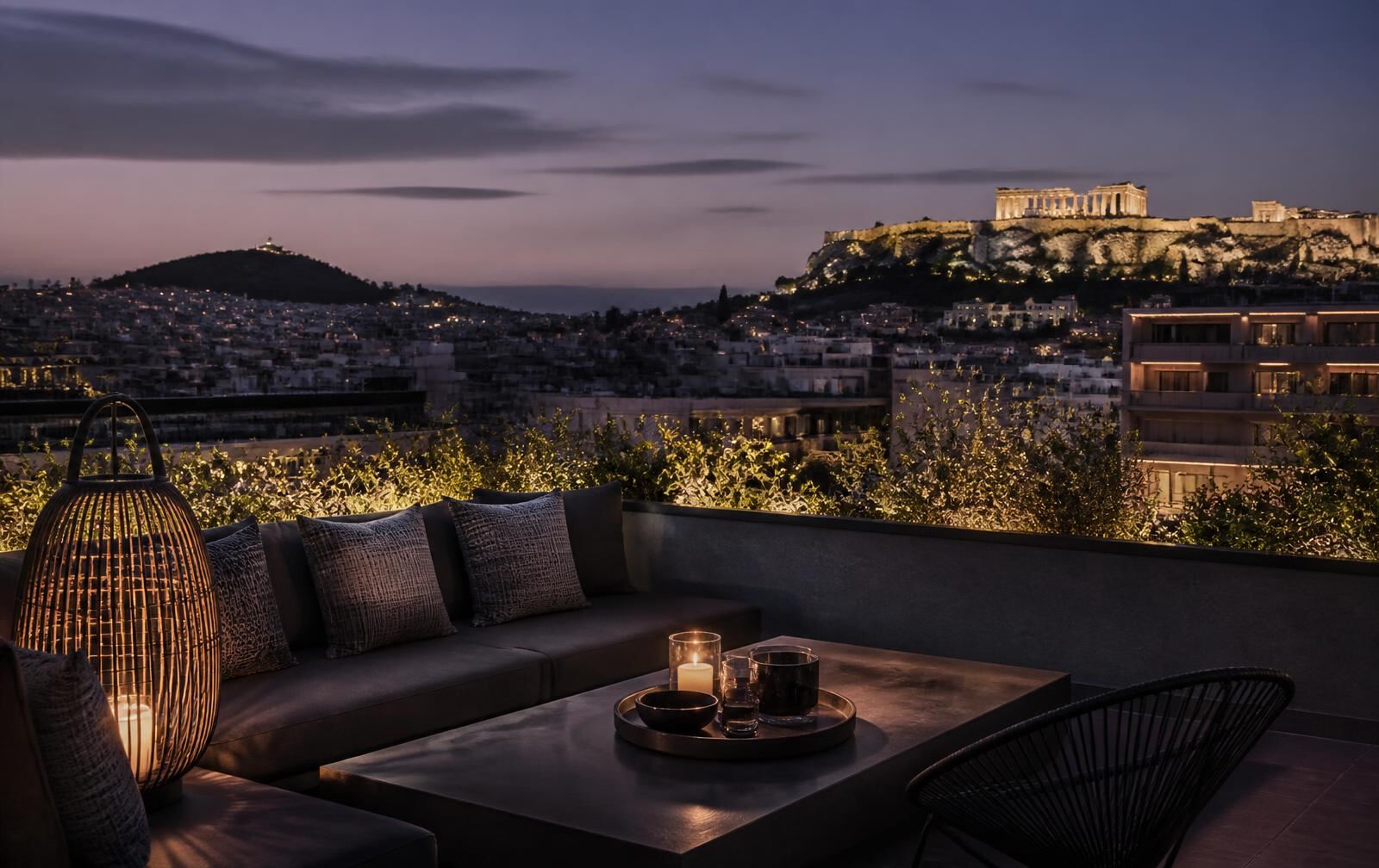 An elegant Athens rooftop at twilight overlooking the illuminated Acropolis and city lights