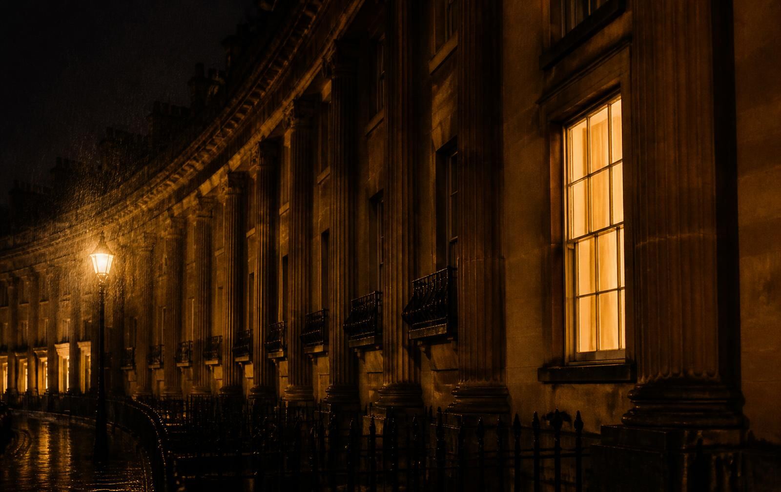 Georgian honey-stone crescent in Bath at night in soft rain with one warm lit sash window