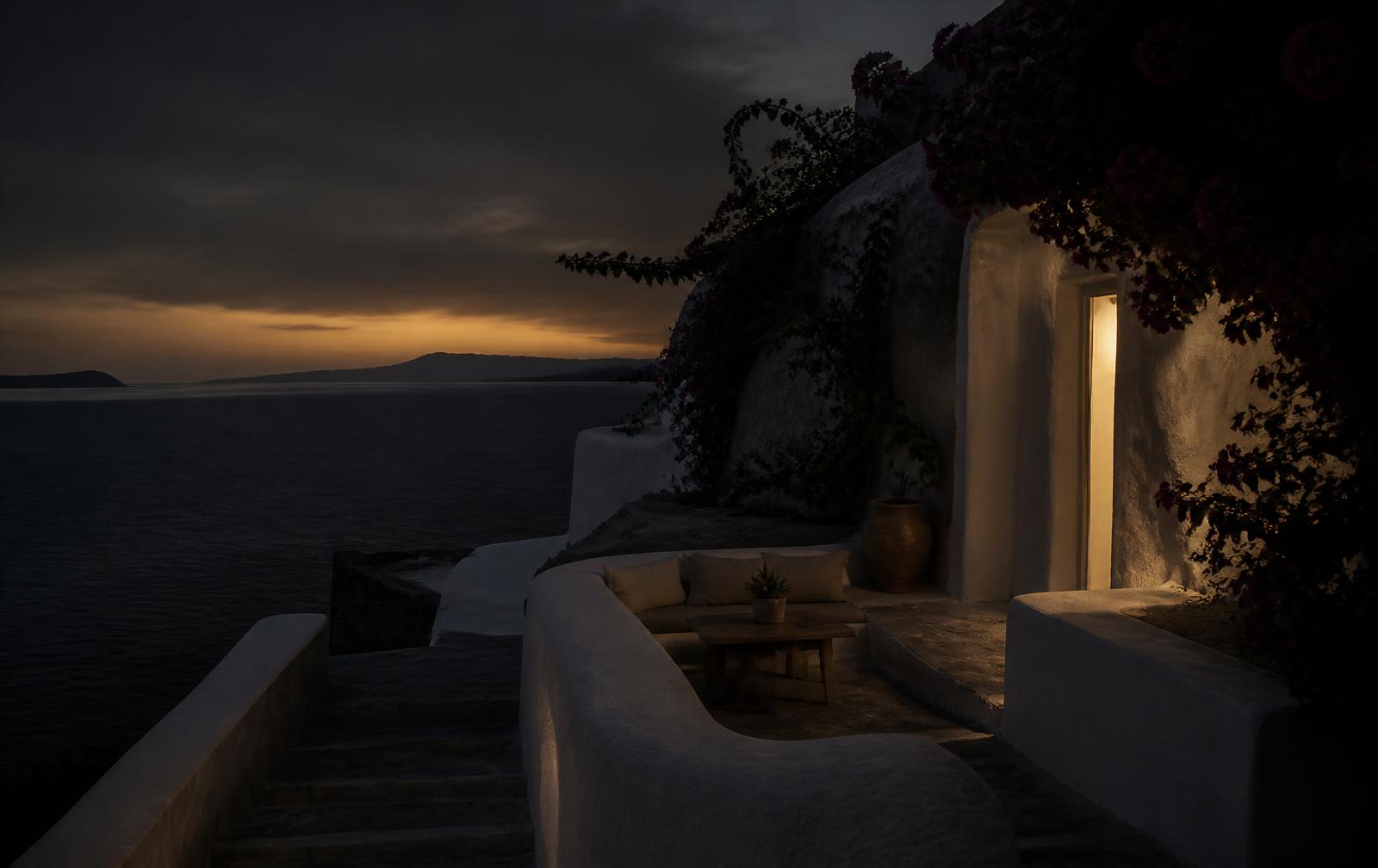 A white stone terrace above a dark Aegean sea at dusk with bougainvillea and one warm doorway light