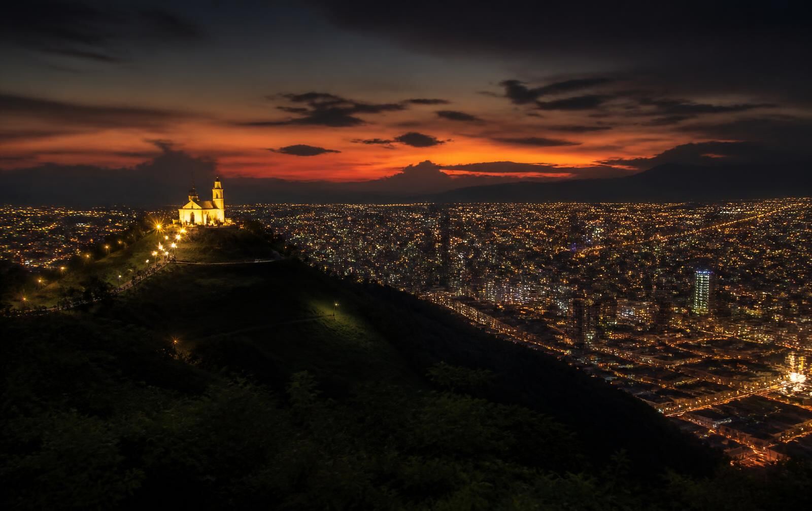 Cali at dusk, the lit San Antonio chapel on its hill above a vast spread of warm city lights