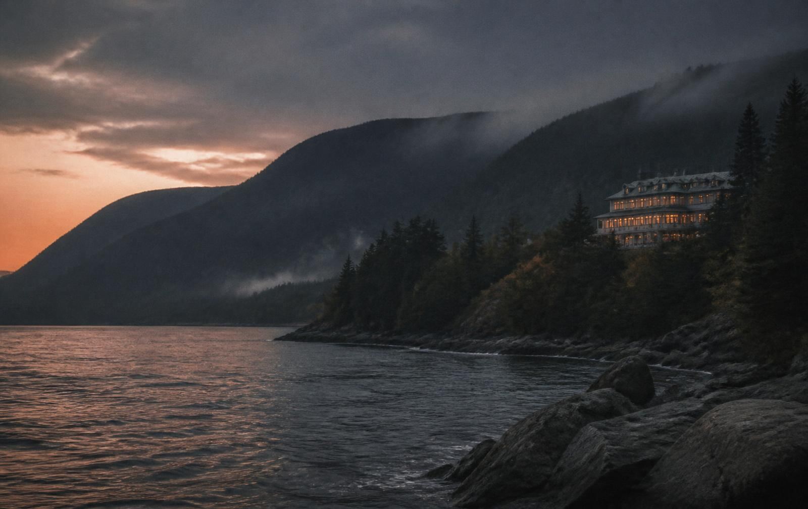 Dark Charlevoix hills meeting the wide Saint Lawrence at dusk with a lit inn above the shore