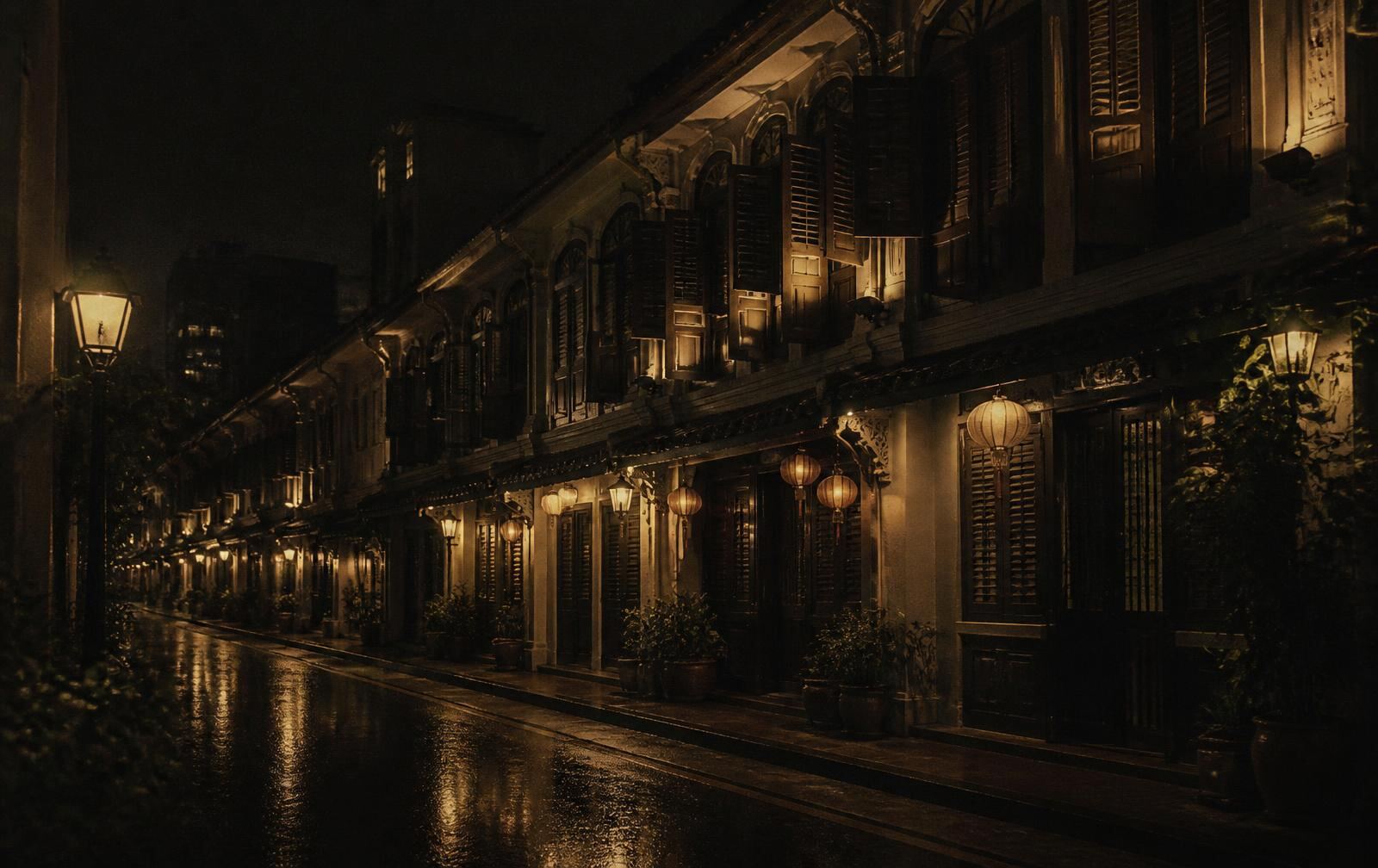 A narrow street of restored shophouses at night with timber shutters, warm lanterns and lamplight reflected on wet pavement