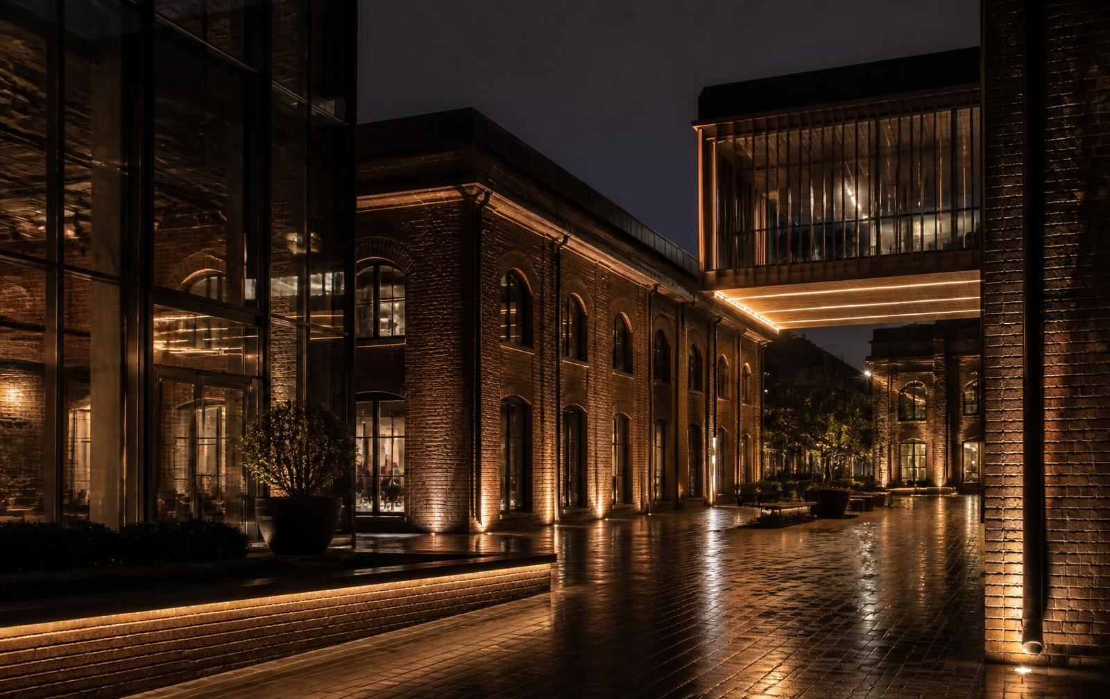 Restored industrial brick buildings with modern glass extensions lit warmly at night in Eindhoven's design district