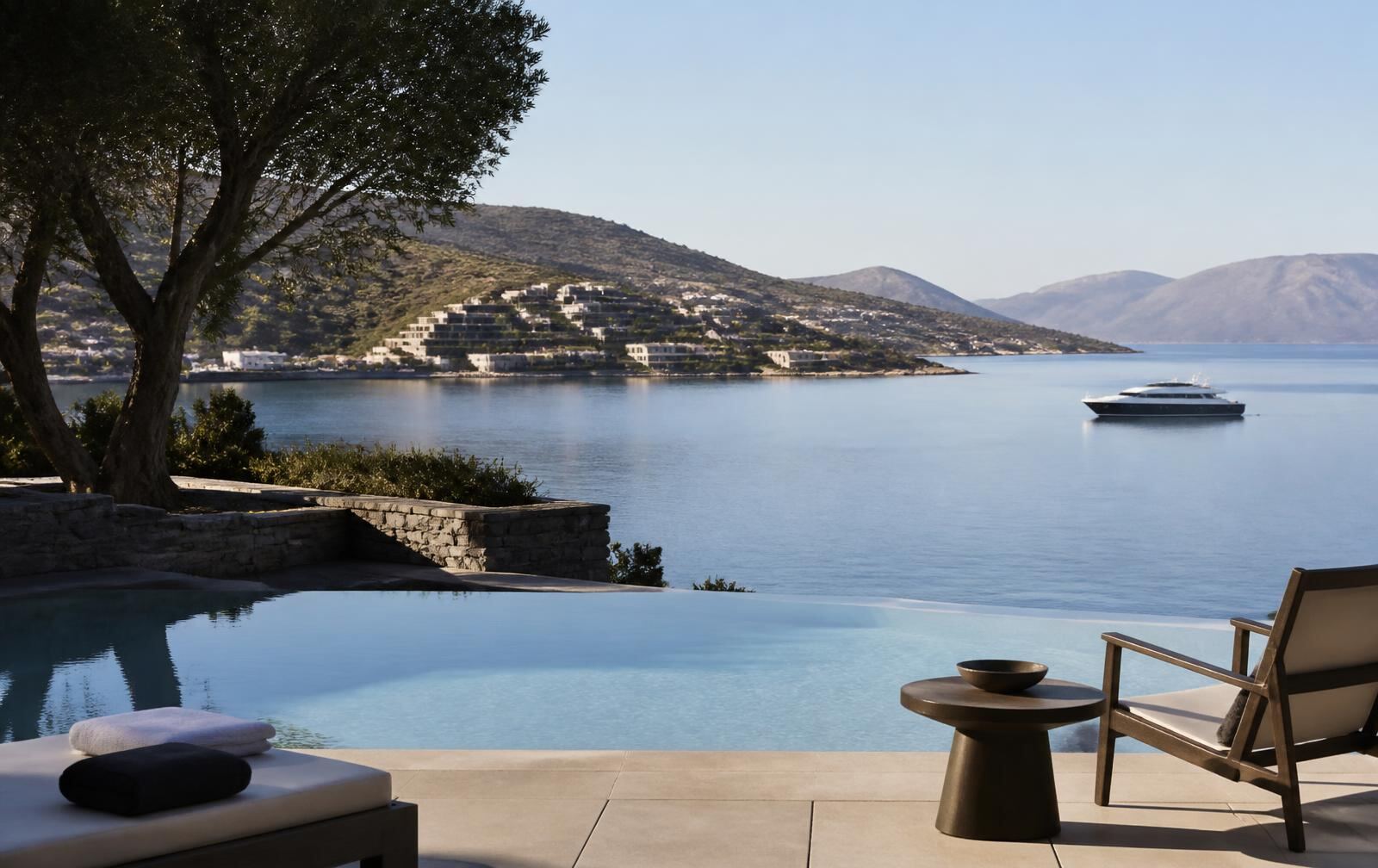 A refined Elounda resort terrace overlooking calm Mirabello Bay and a distant yacht