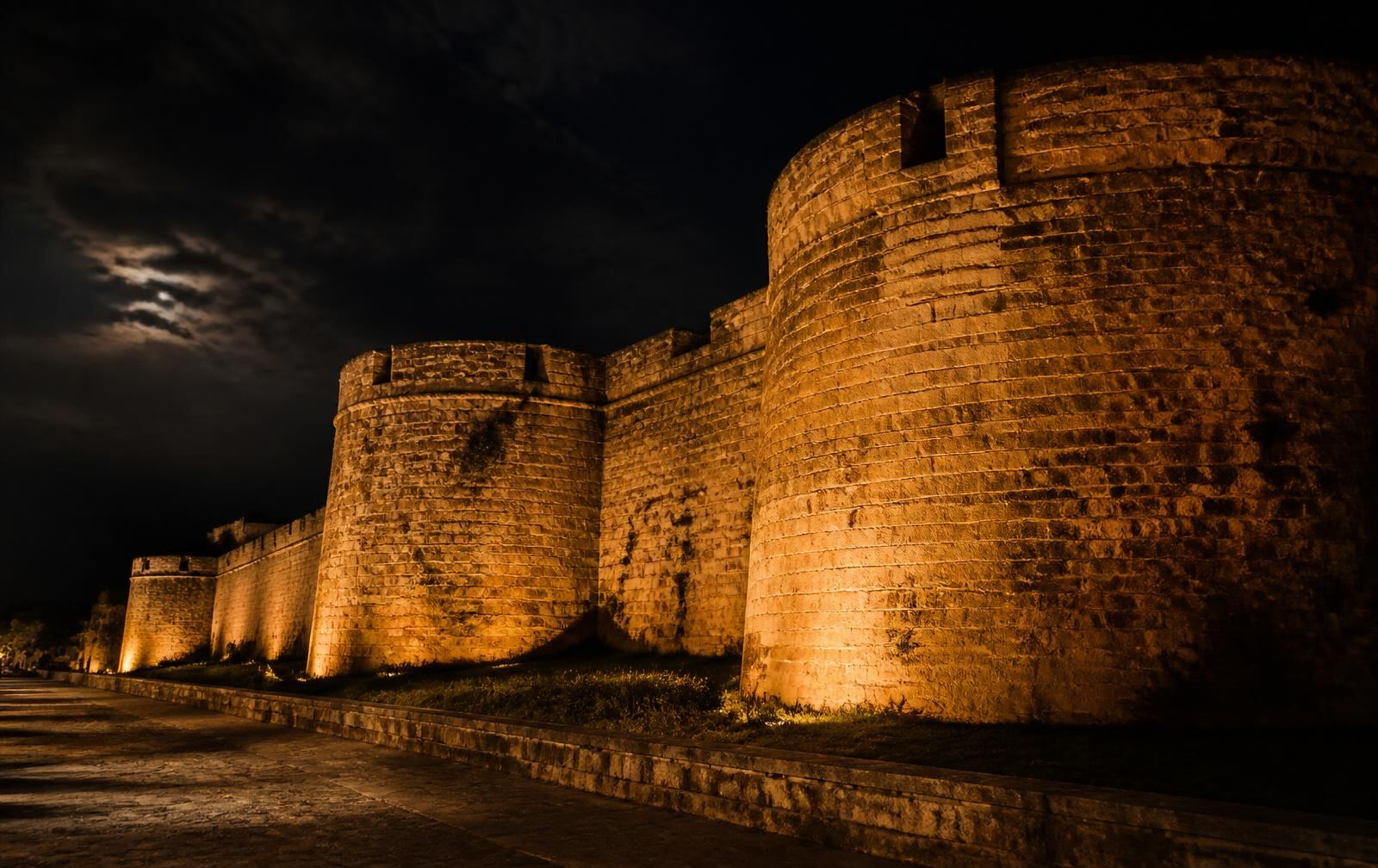 Massive medieval Venetian walls of Famagusta lit warmly against a black night sky