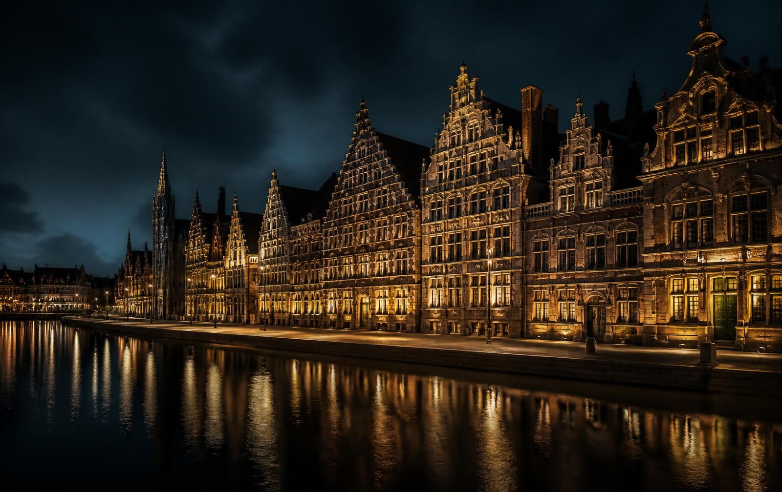 Historic guild houses lit along a wide Ghent canal at night with reflections across dark water