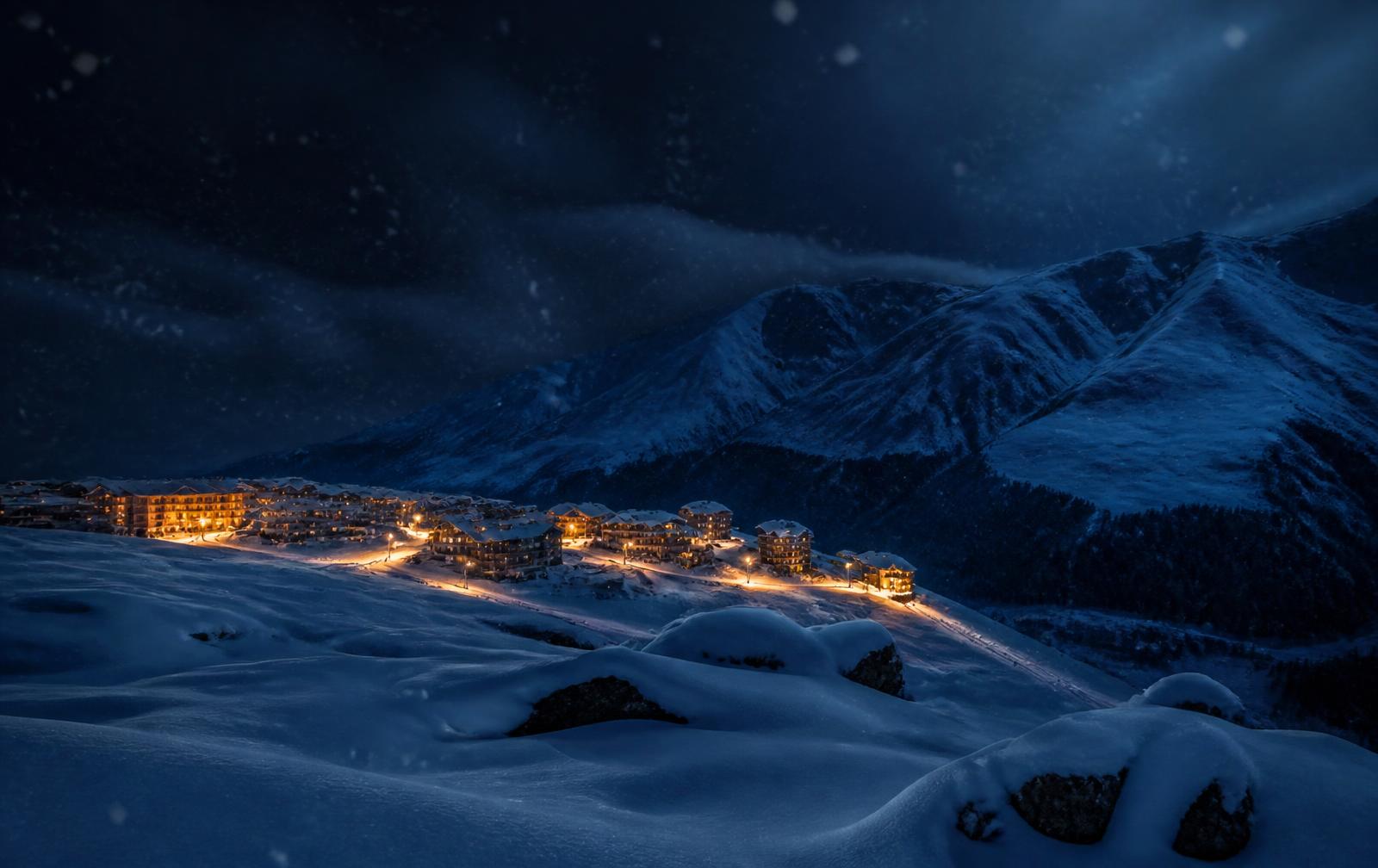 Gudauri ski resort at night in falling snow, warm hotel windows glowing in the dark mountain valley