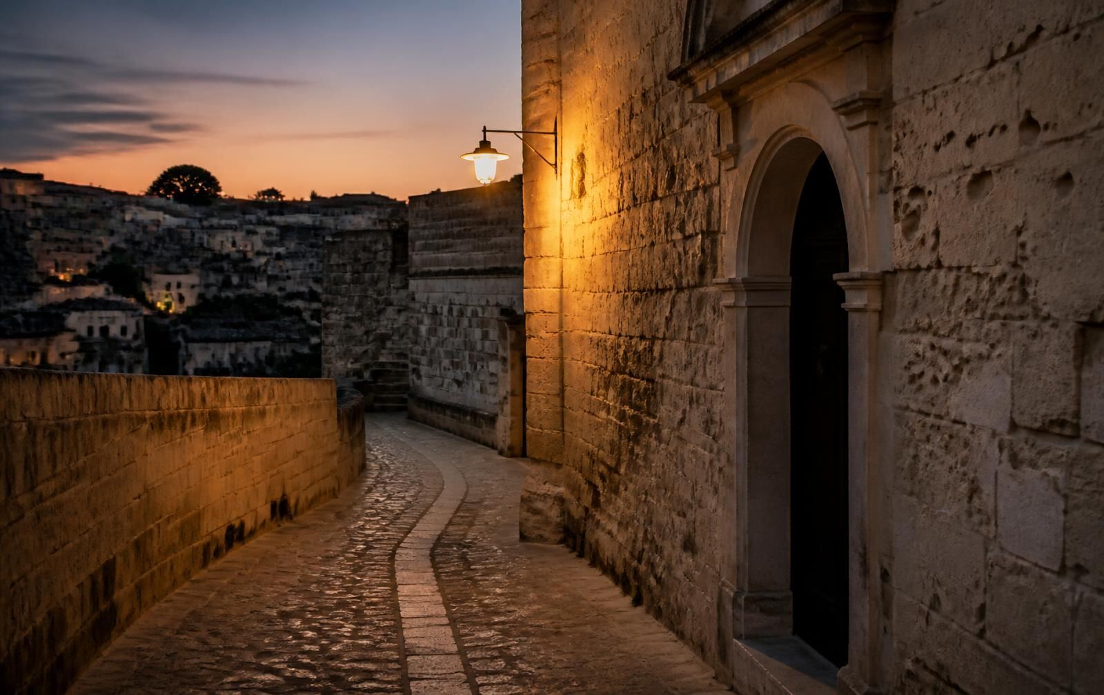 Empty pale limestone street in an old hill city at dusk, warm lamplight on weathered stone walls and a shadowed arched doorway