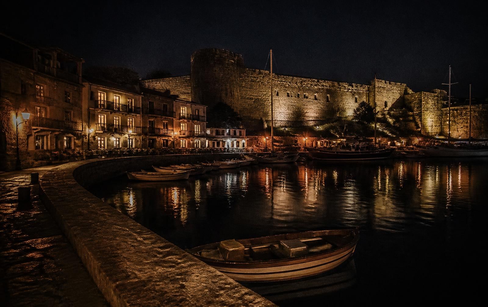 Kyrenia old harbour at night with the castle wall lit and warm reflections on dark water
