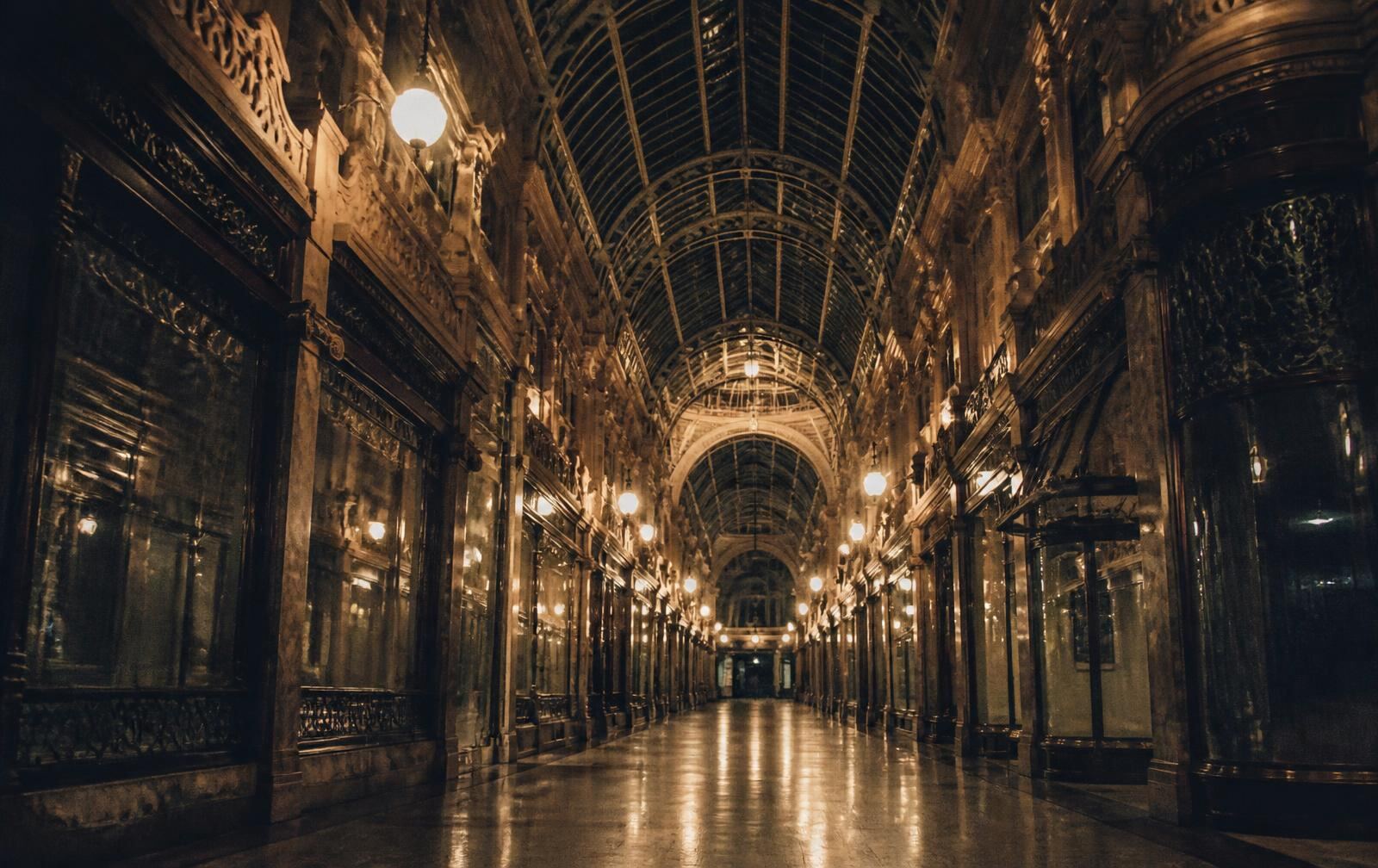Victorian Leeds arcade at night with ironwork glass roof, warm lamps and an empty polished floor