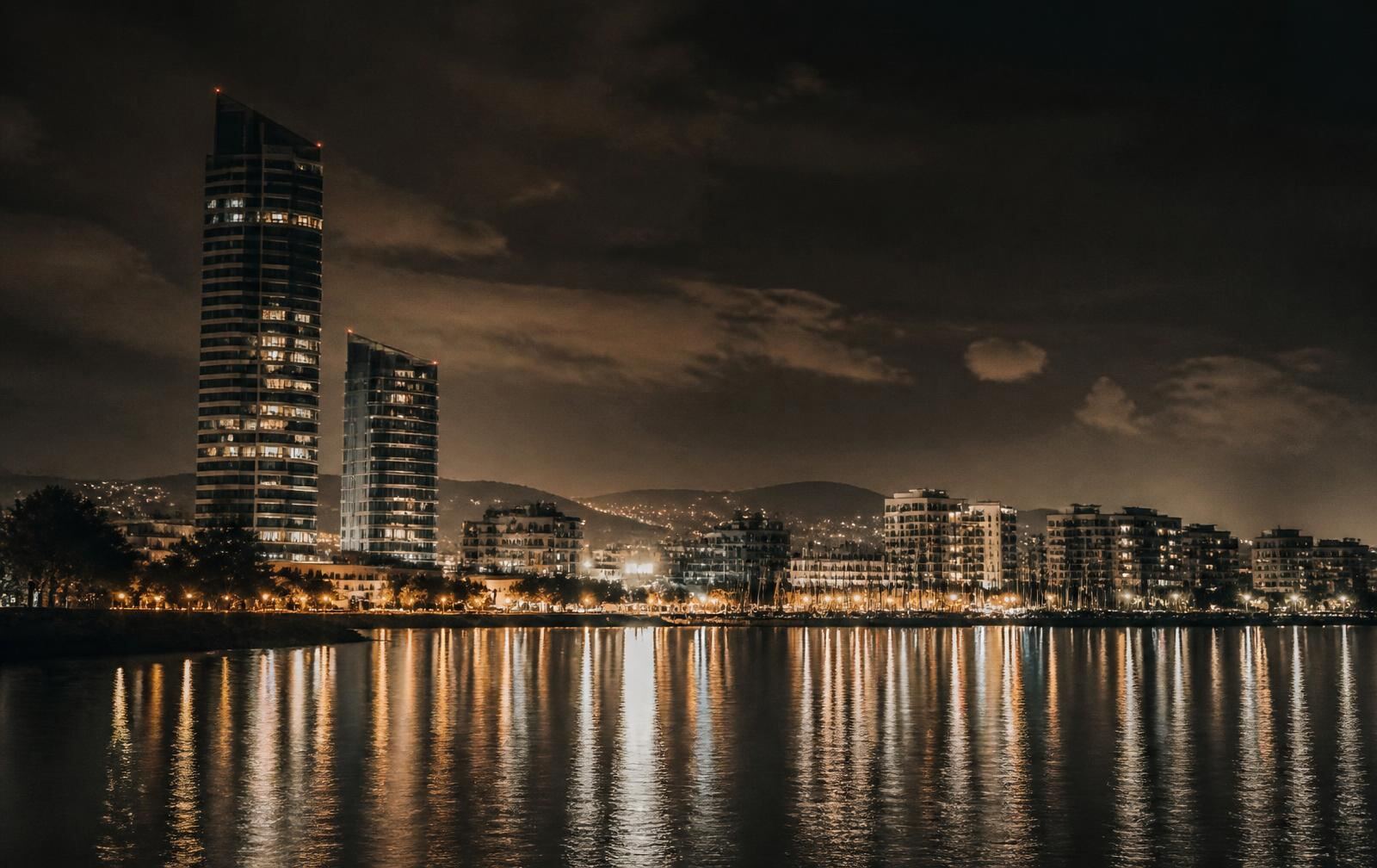 Limassol seafront at night with lit towers and marina reflections on dark water