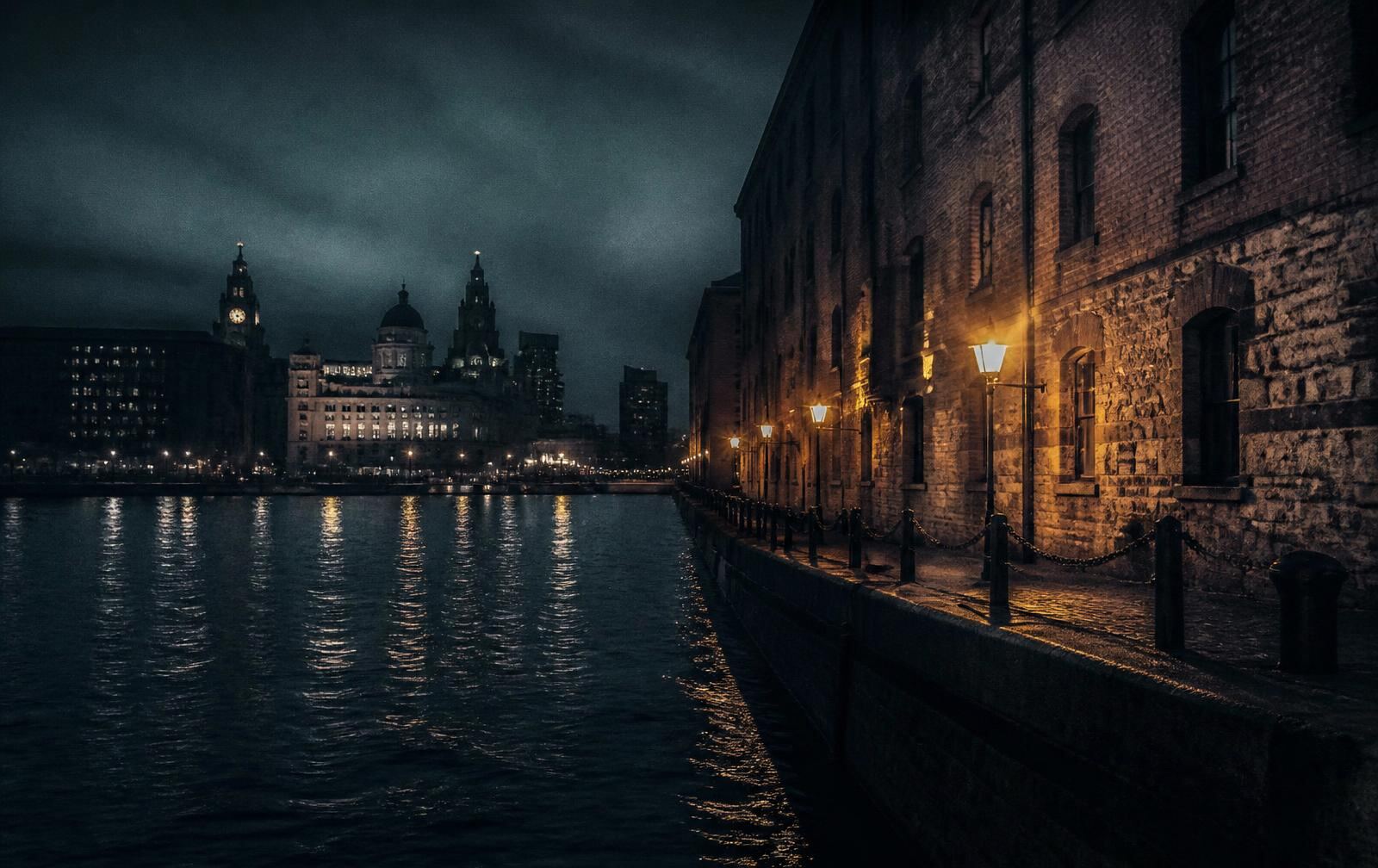 Liverpool waterfront at night with dark river water, dock warehouse stone and distant lit buildings