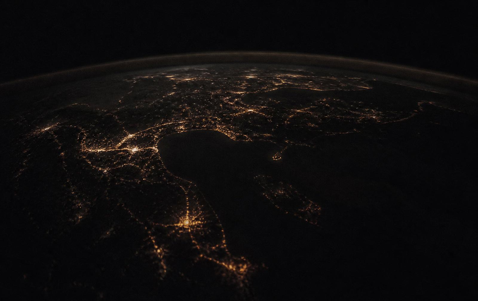 The curve of the earth at night, scattered with distant golden city lights