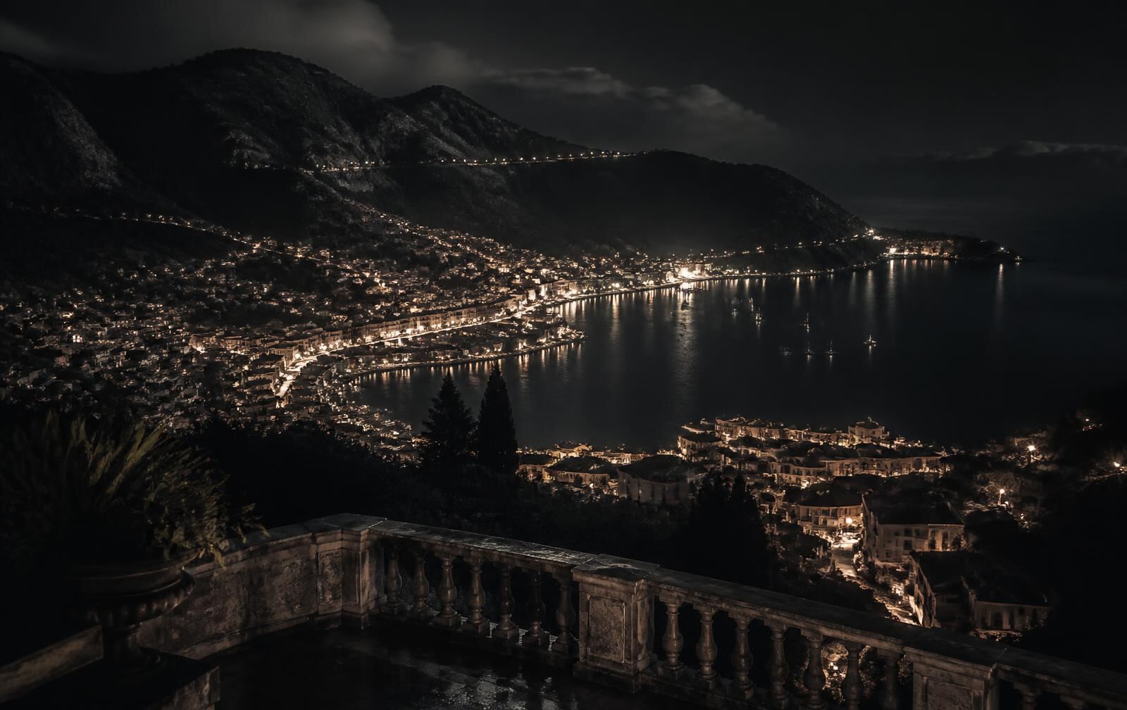 An elevated island city at night with terraced lights descending to a dark bay