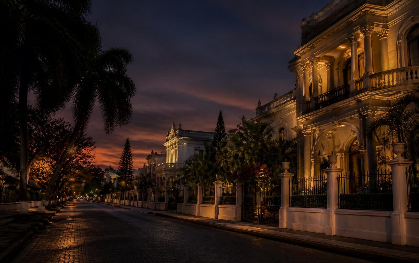 Paseo de Montejo in Mérida at dusk, lit colonial mansions and palms along a quiet avenue