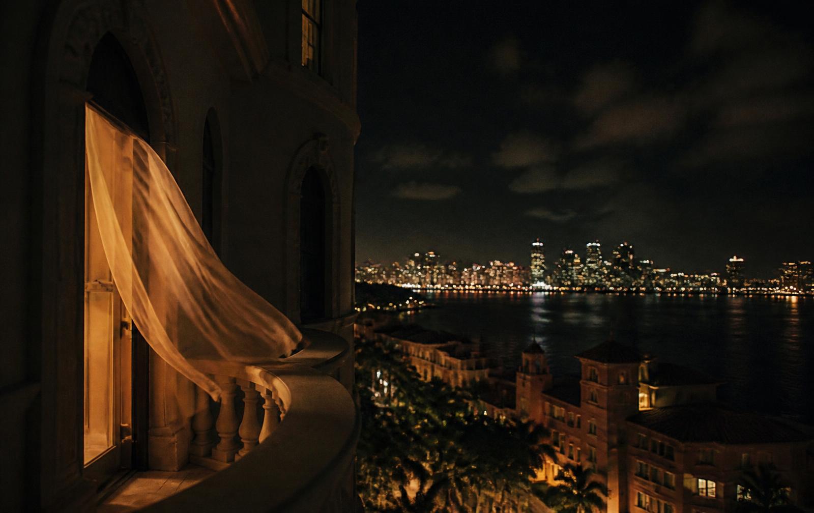 Miami skyline at dusk with warm balcony light against a darkening sky over Biscayne Bay