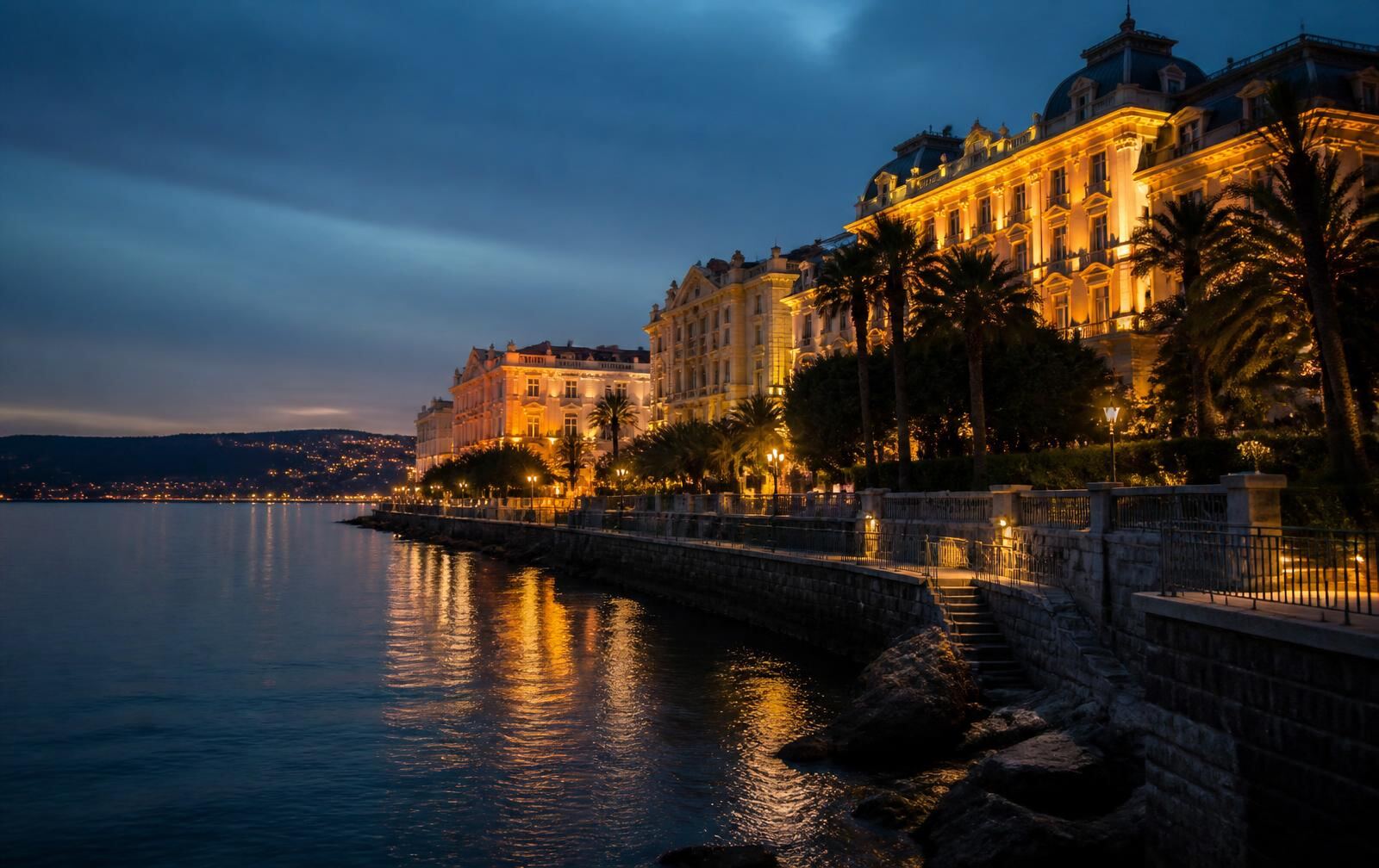 The Opatija riviera at night — a lamp-lit seaside promenade, grand historic façades and calm water under a dark sky