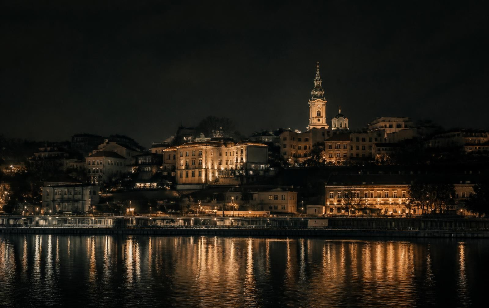 A warm candlelit interior at dusk with gold light and a Serbian river city skyline beyond the window