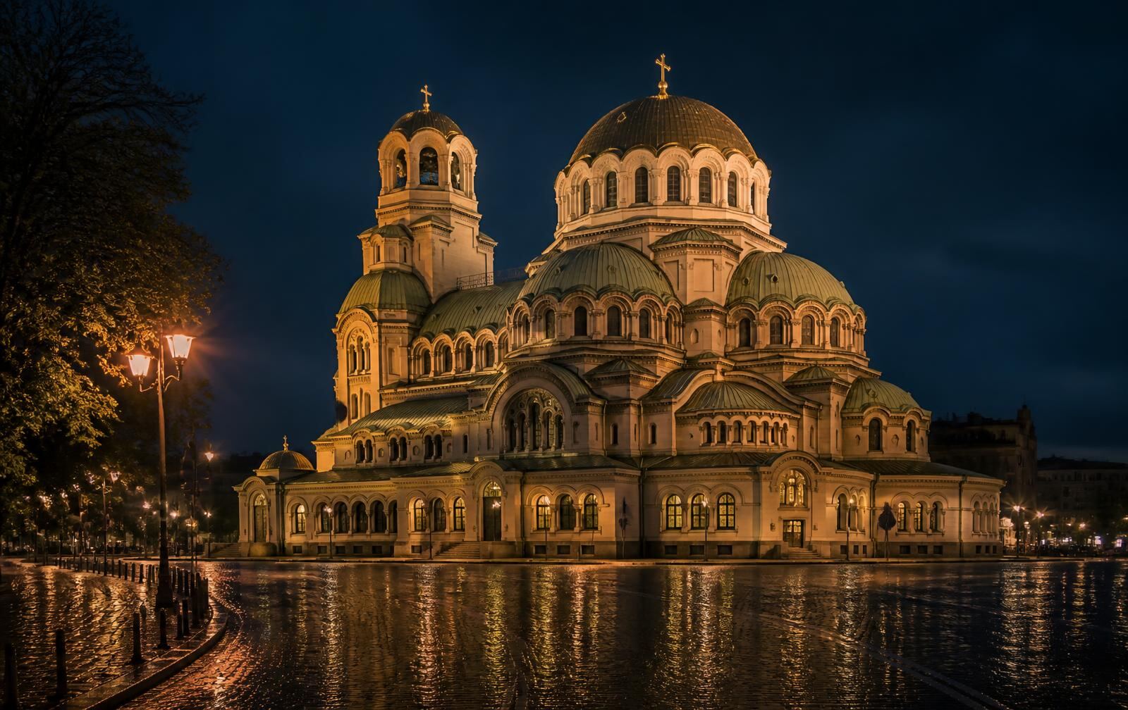 Sofia's Alexander Nevsky Cathedral glowing at night above rain-wet cobblestones