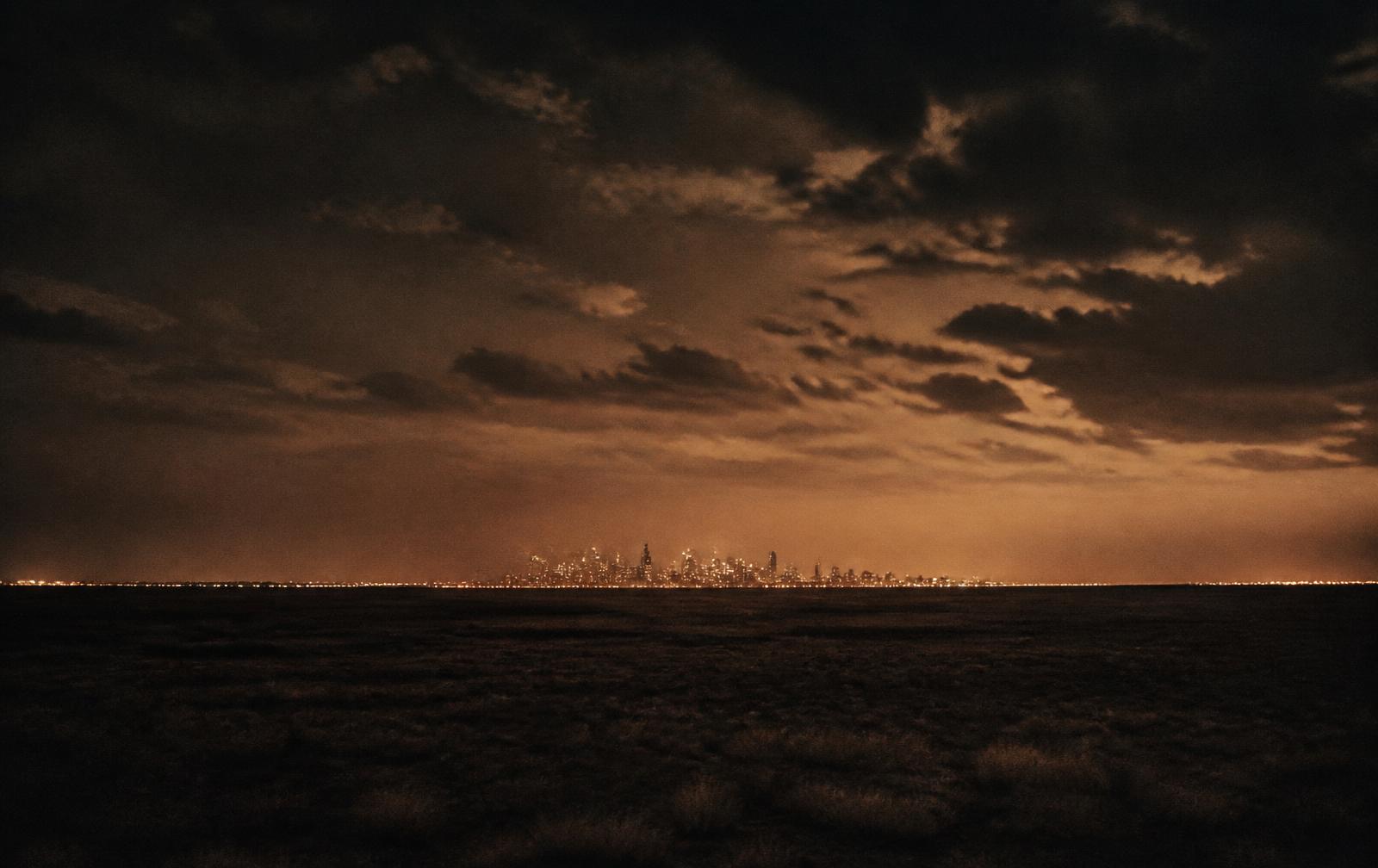 A sleek, dimly lit high-rise interior at night with a wide Texas skyline glowing beyond floor-to-ceiling glass